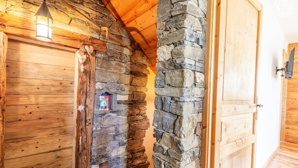 Ein Holzinnenraum mit Steinwand, Holztür und kleinem Fenster mit einer Zeitschrift.