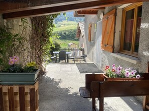 A patio with a wooden bench, a table, and chairs, surrounded by potted plants and a view of a rural landscape. - L'entre Deux - VAL CENIS (VAL CENIS)