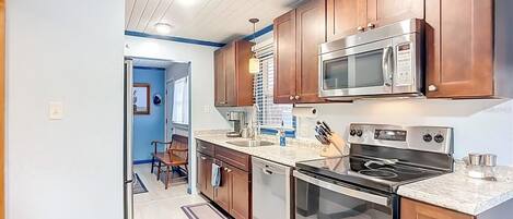 A kitchen with wooden cabinets, a microwave, a stove, and a dishwasher.