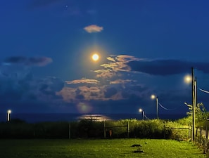 A nighttime landscape with a prominent moon, street lamps, and a grassy field. - Cambelas second westernmost point in Europe, Beaches (São Pedro da Cadeira)
