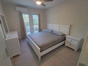 Ein Schlafzimmer mit einem Bett, einem Nachttisch, einer Kommode und einem Deckenventilator.