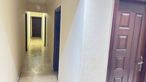 Ein Flur mit einer Tür am Ende, einer Leuchte an der Decke und einer strukturierten Wand.
