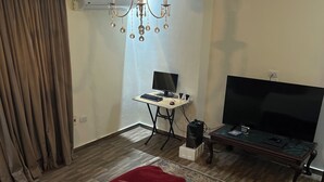 Ein Hotelzimmer mit Bett, Schreibtisch mit Computer, Fernseher und einer Kandelaber.