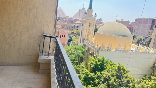 Ein Balkon mit Metallgeländer und Blick auf eine Stadtlandschaft mit Gebäuden und einer Moschee mit Kuppel.