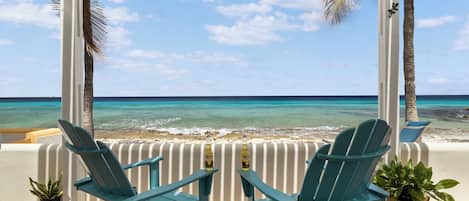 Une vue sur la plage avec deux chaises et une bouteille de bière sur une table.