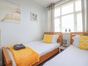 Ein Zimmer mit zwei Betten, einem Fenster mit Jalousien, einem Bild an der Wand und einer Lampe auf dem Nachttisch.