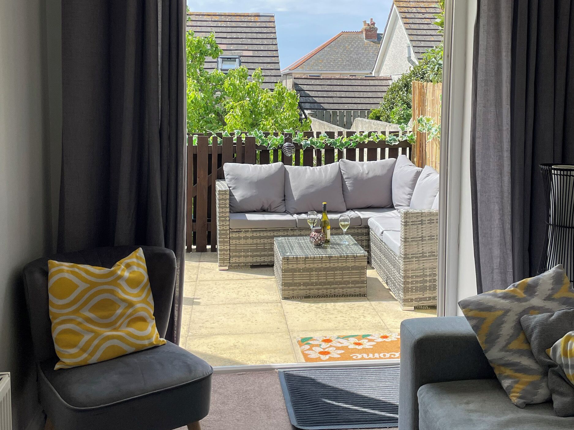 Eine Terrasse mit einer Couch, zwei Stühlen, einem kleinen Tisch und einem Zierteppich.