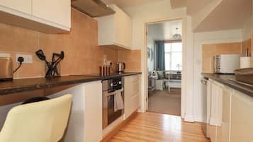 Uma cozinha moderna com bancada de madeira, eletrodomésticos de aço inoxidável e vista para uma sala de estar.