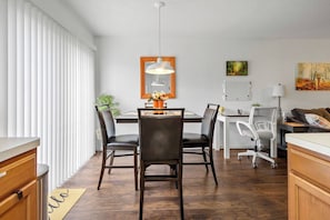 A modern dining area with a wooden table, black chairs, a pendant light, and a whiteboard on the wall. - The Oaks at Burnell – Private Houston Home (Houston)