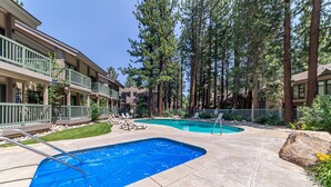 A pool area with two pools, lounge chairs, and tall trees. - Centrally Located Townhouse - Jacuzzi & Parking! (Mammoth Lakes)