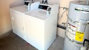 Ein kleiner Hauswirtschaftsraum mit einem weißen Durchlauferhitzer, einem Bedienfeld und einer Wasserpumpe.