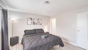 Ein Schlafzimmer mit Bett, Nachttisch, Lampe und Tür.