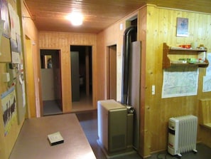 Ein Holzinnenraum mit einem Kühlschrank, einem Heizkörper und einer Tür zu einem anderen Zimmer.