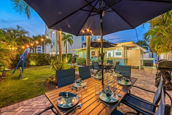 Un espace extérieur aménagé pour les repas, avec des tables, des chaises et des parasols.