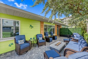 Eine Terrasse im Freien mit Korbmöbeln, einer Feuerstelle und einer grünen Wand.