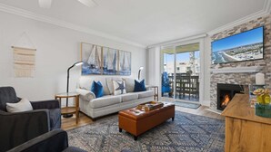 Un salon comprenant un canapé, des fauteuils, une table basse, une cheminée et un grand téléviseur.