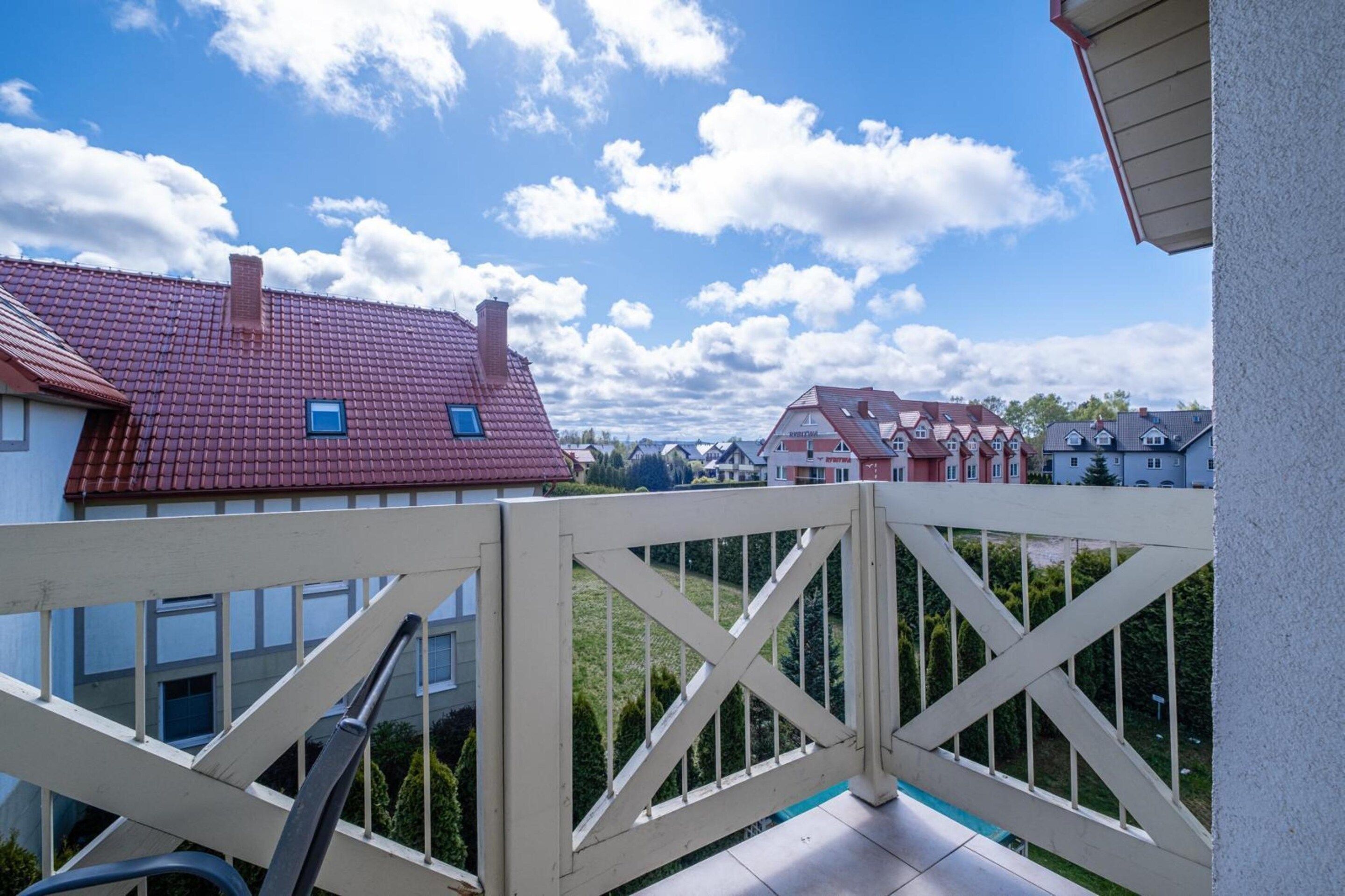 Un quartiere residenziale con case, cielo sereno e un recinto bianco.