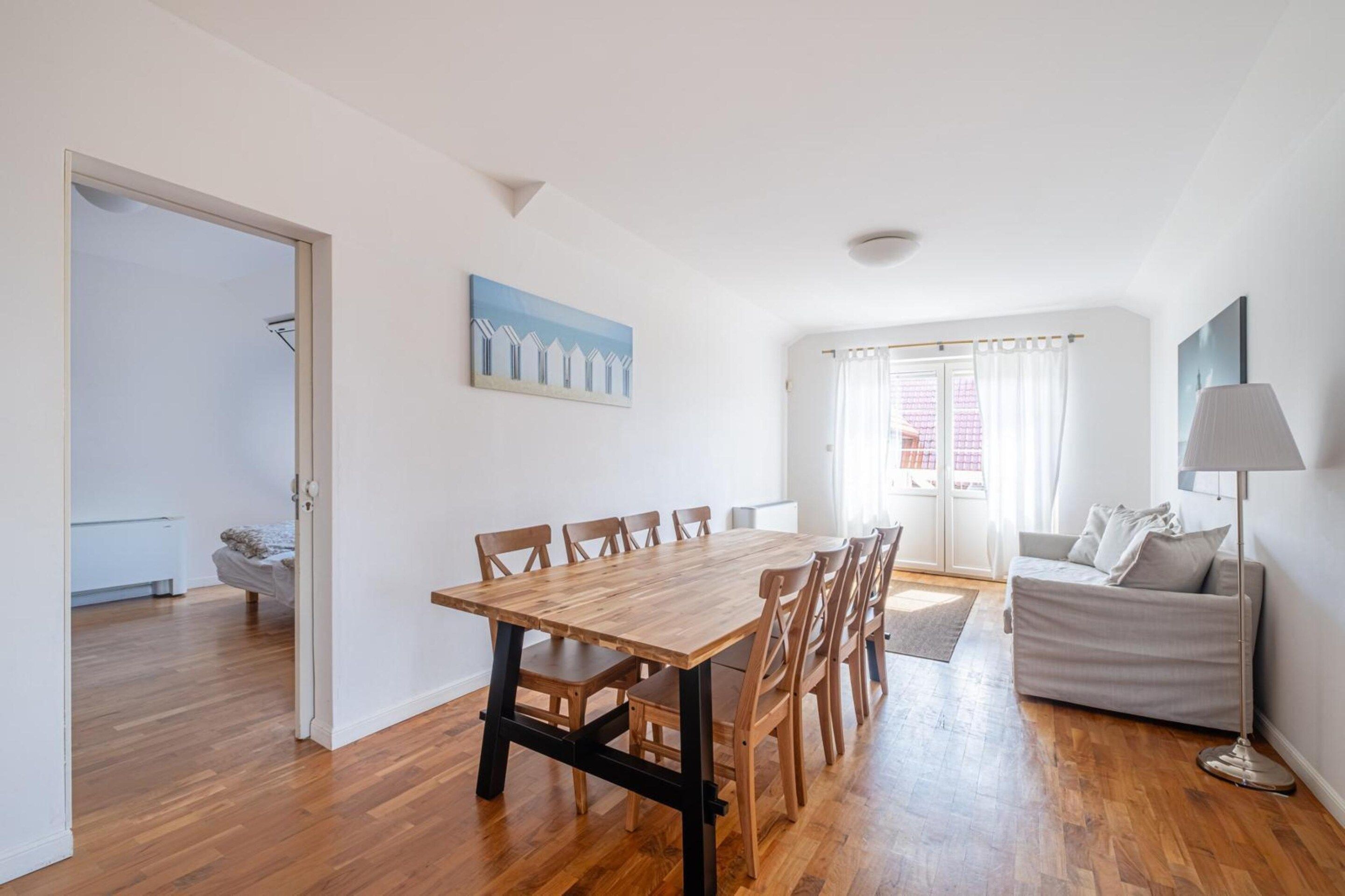 Un vaste espace de vie comprenant une table à manger en bois, un canapé et une lampe.