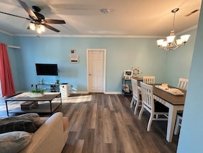 A living room with a sofa, coffee table, TV, and a dining area with a table and chairs. - Dog-Friendly 2BR/2BA Condo Near Rehoboth Beach (Rehoboth Beach)