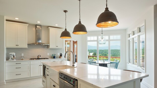 A modern kitchen with white cabinetry, stainless steel appliances, and pendant lighting.