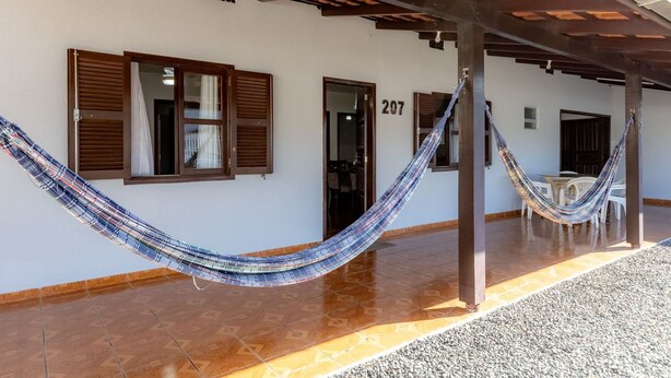 A building with a number '207' on the wall, a hammock hanging between pillars, and a tiled floor. - Casa com Churrasqueira e Rede a 210 m da Praia (Navegantes)