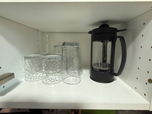 Ein Regal mit einer schwarzen Kaffeemaschine und drei klaren Glaskästen.