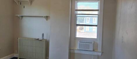 A room with a ceiling fan, radiator, window with blinds, and a radiator on the floor.