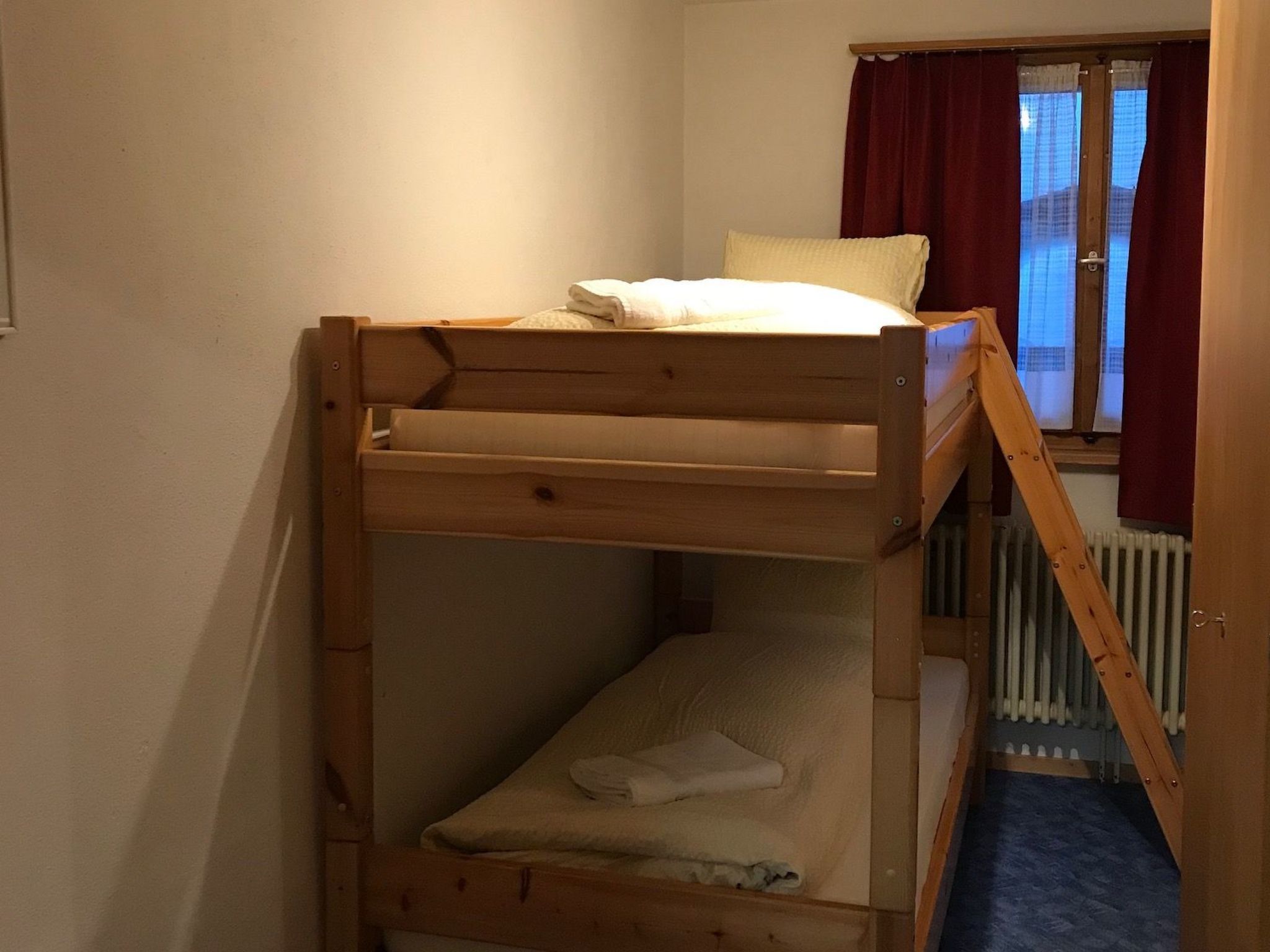 Een stapelbed met raam en gordijnen.