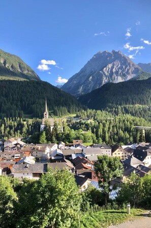 A town nestled in a valley with a prominent church and mountains in the background. - Ferienwohnungen Chasa Valär, (Scuol) by Interhome (Scuol)