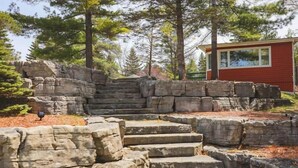 A stone staircase leading up to a red building surrounded by trees.