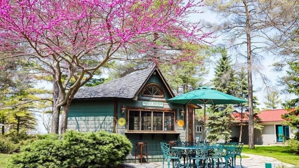 A quaint building with a green exterior, a sign reading 'Weed It and Hop,' and a patio with outdoor seating.