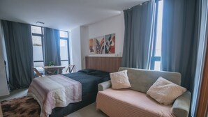 Et soveværelse med to senge, en sofa, et lille bord og et billede på væggen.