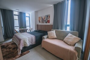 Ein Schlafzimmer mit zwei Betten, einem Schlafsofa, einem kleinen Tisch und einem Bild an der Wand.