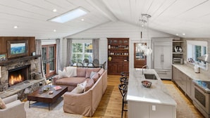 A spacious living area with a fireplace, a sofa, a coffee table, and a kitchen with a central island. - Sunset Nest, Walk to Town (Highlands)