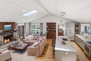 A spacious living area with a fireplace, a sofa, a coffee table, and a kitchen with a central island. - Aschmeyer's, Walk to Town (Highlands)