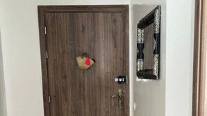 A hallway with a wooden door, a small woven bag hanging on the wall, and a black bag on the floor. - Nice apartment (Marrakech)