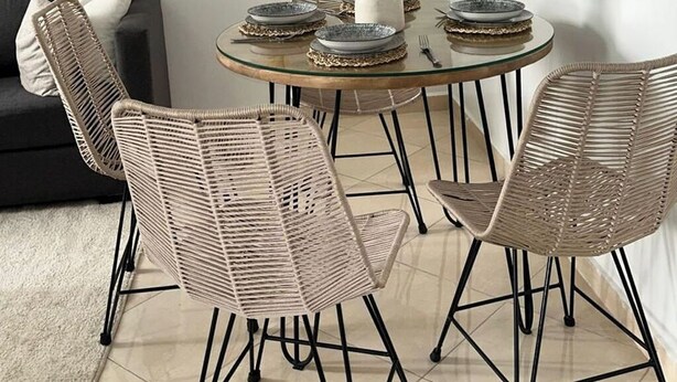 A dining area with a round glass table, four wicker chairs, and three wall-mounted mirrors. - Nice apartment (Marrakech)