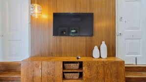 Um balcão de recepção de madeira com uma TV de tela plana, dois vasos brancos e cestos de fibra.