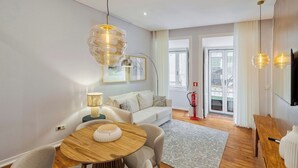 Uma sala de estar moderna com uma mesa de madeira redonda, um sofá e uma televisão.