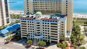 A multi-story hotel with a central courtyard, a pool, and a beach view. - Bundle of Three (3) Beachfront Penthouse Suites! Tons Of Resort Amenities! (Myrtle Beach)