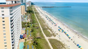 A coastal hotel with a long beachside promenade, a pool, and a pier extending into the sea. - Bundle of Three (3) Beachfront Penthouse Suites! Tons Of Resort Amenities! (Myrtle Beach)