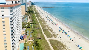 A coastal hotel with a long beachside promenade, a pool, and a pier extending into the sea. - Bundle of Two (2) Beachfront Penthouse Suites! Tons Of Resort Amenities! (Myrtle Beach)