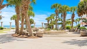 A paved walkway lined with palm trees and large planters, leading to a beach with the ocean in the background. - Bundle of Two (2) Beachfront Penthouse Suites! Tons Of Resort Amenities! (Myrtle Beach)