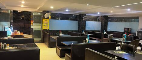 Un restaurant avec des banquettes, des tables et un grand écran.