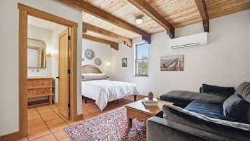 A bedroom with a bed, a wooden wardrobe, a bedside table, a nightstand, a window, and a ceiling fan.