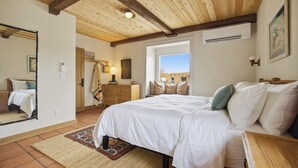 Un dormitorio con una cama grande, vigas de madera en el techo, una ventana y un espejo.