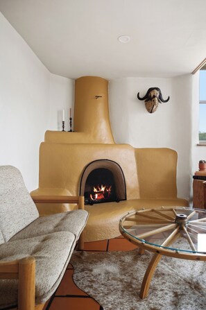 A cozy living room with a fireplace, a sofa, a glass table, and a decorative skull on the wall. - Hey House (Buena Vista)