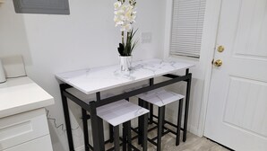 Un bureau blanc avec un plateau en marbre, une structure en métal noir et deux étagères.