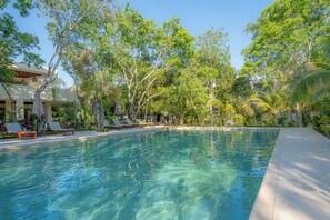 A clear swimming pool surrounded by lounge chairs and trees. - 3-bedroom house in charming Playa del Carmen with pool! (Playa del Carmen)