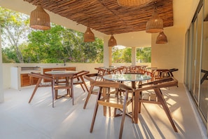 An outdoor patio with wooden furniture, woven ceiling lights, and a view of trees. - 3-bedroom house in charming Playa del Carmen with pool! (Playa del Carmen)
